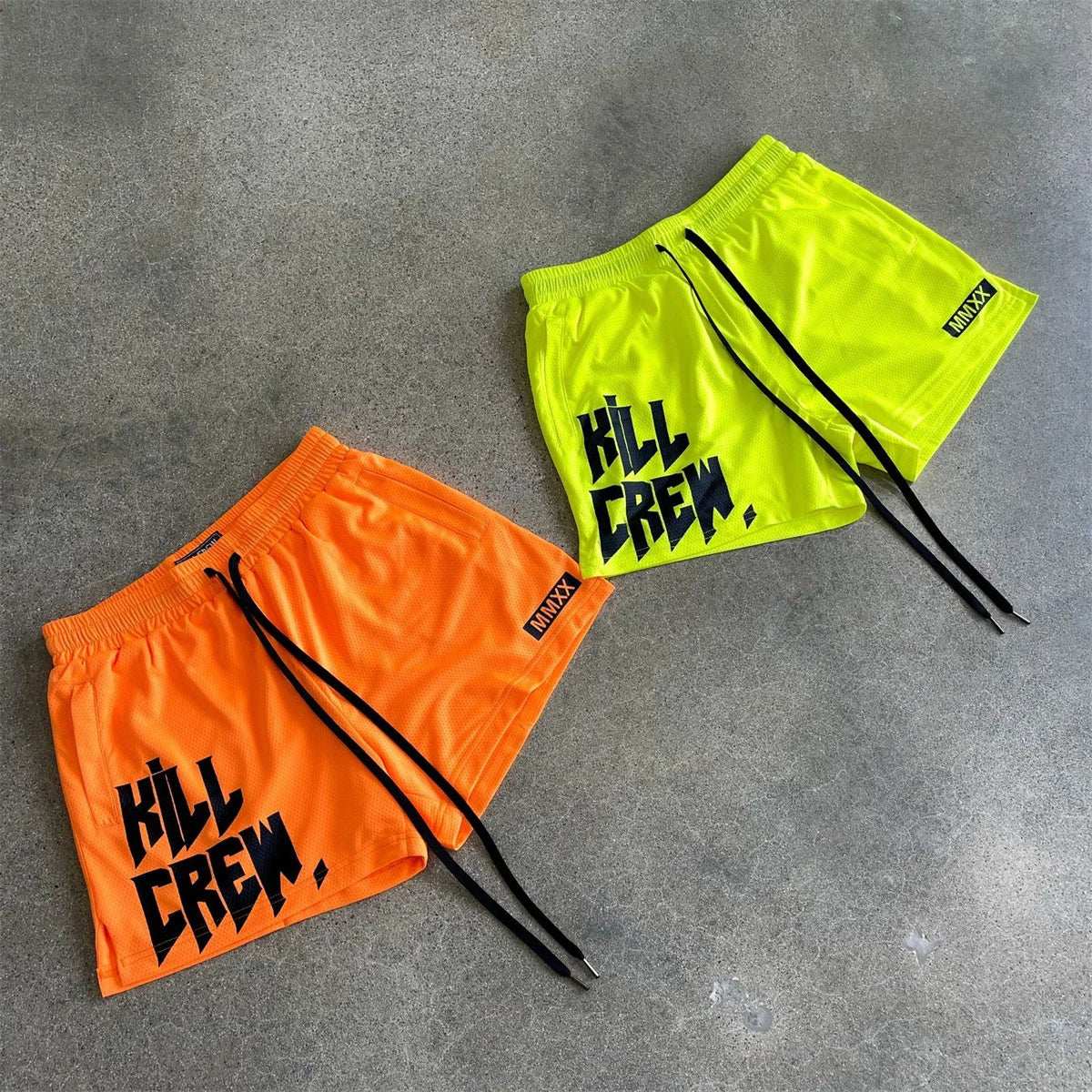 Casual Quick Dry beach shorts in vibrant orange and yellow, featuring bold graphic text on a concrete background.