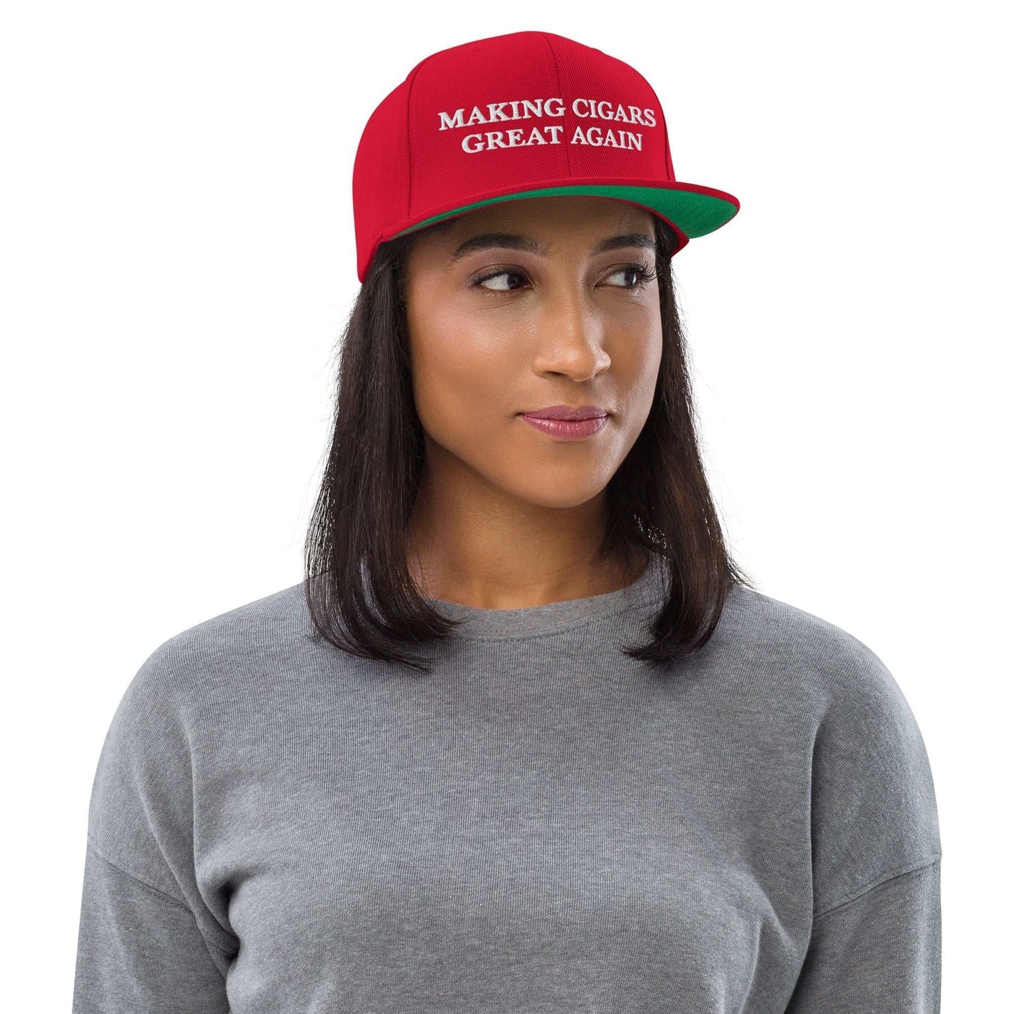 Red snapback hat with "Making Cigars Great Again" text, worn by a person.