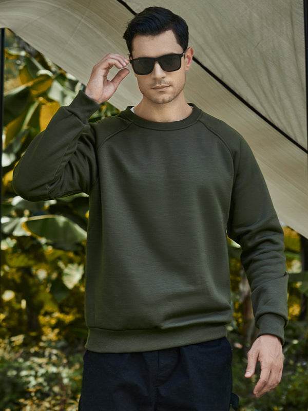 casual raglan sleeve crew neck sweatshirt in olive green on male model outdoors
