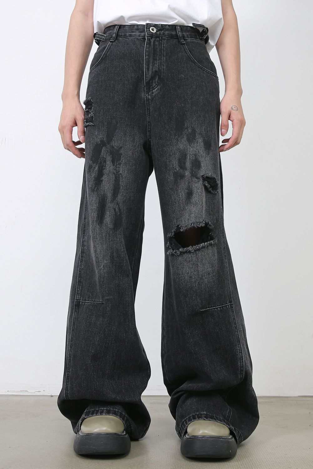 Men's distressed baggy jeans with raw hem and black wash.