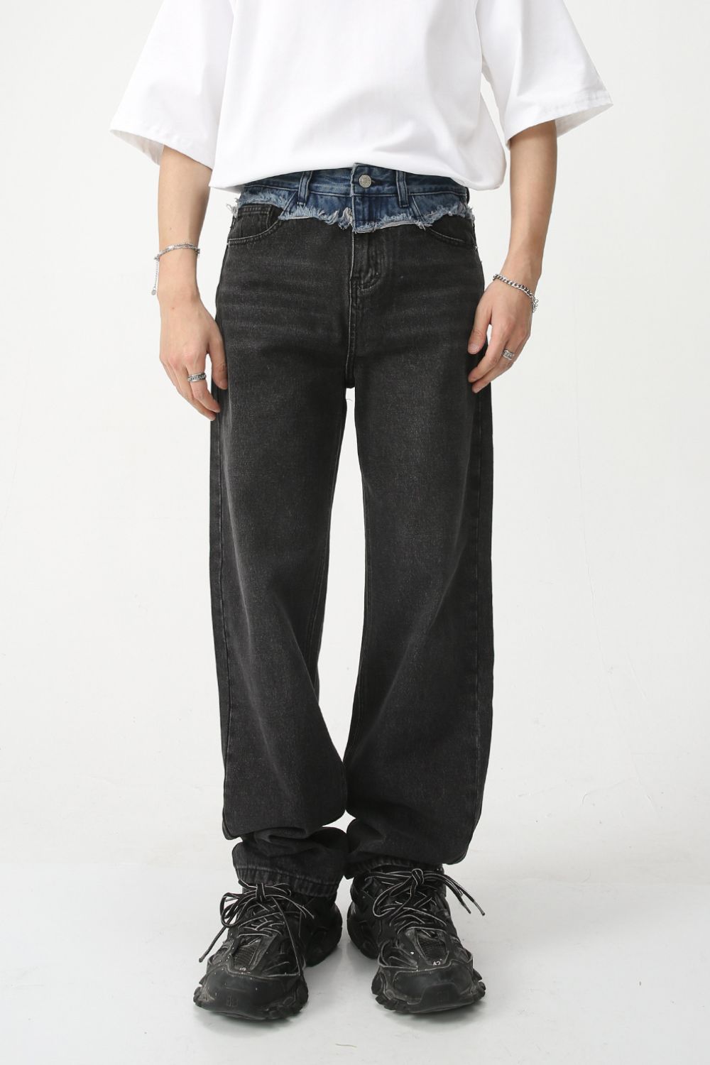 Men's spliced raw hem straight leg jeans, black fabric, modeled with a white shirt and black shoes.