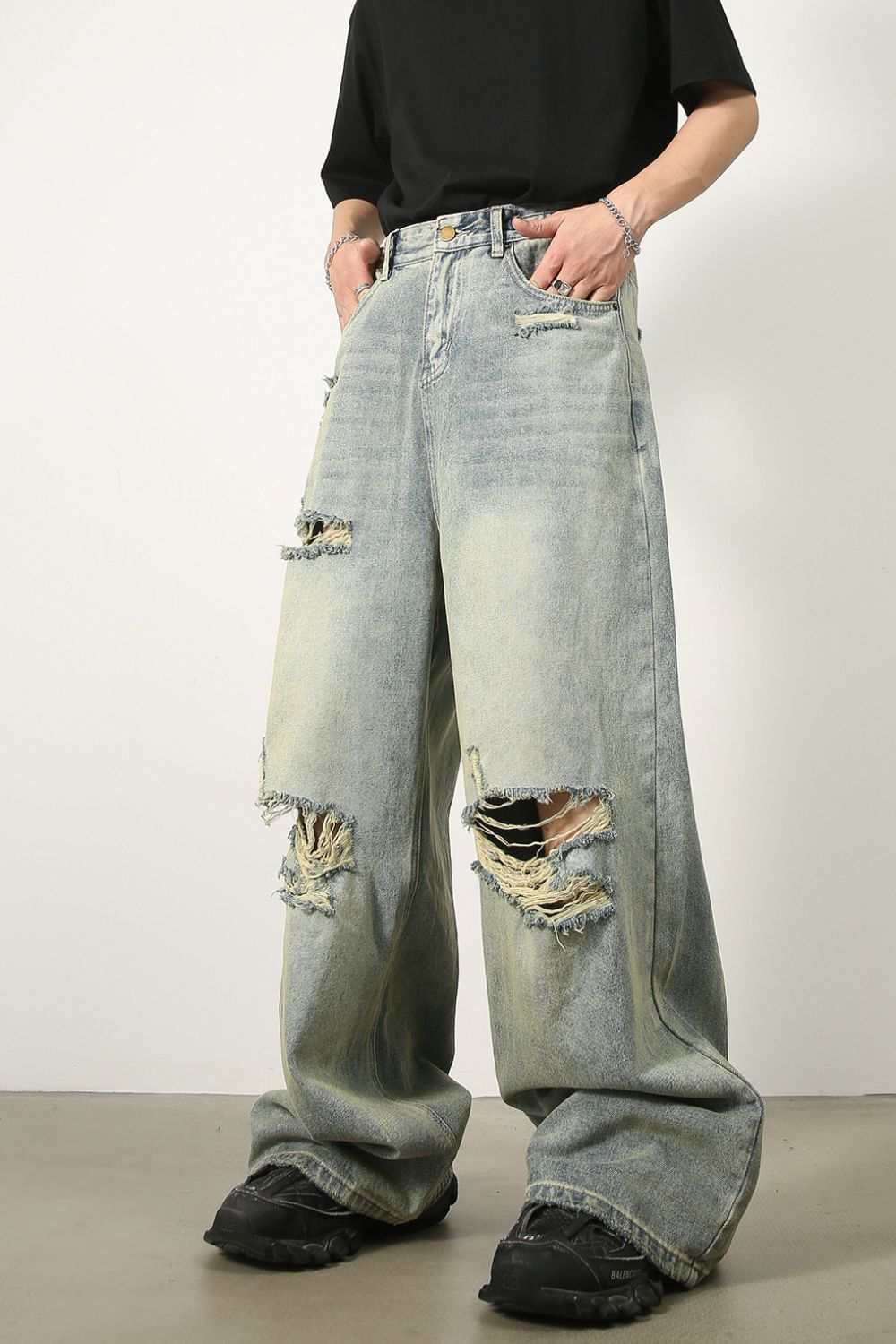 Men's distressed wide leg jeans with raw hem and vintage look.
