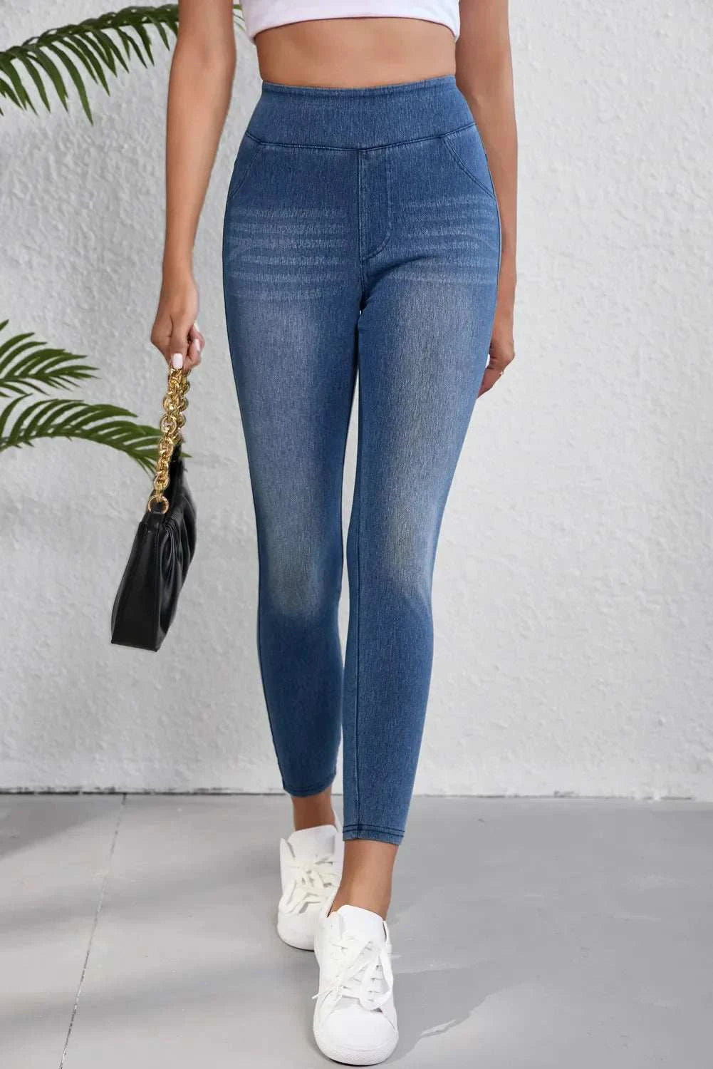 High waist skinny jeans with pockets and moderate stretch, worn by model holding a black bag.