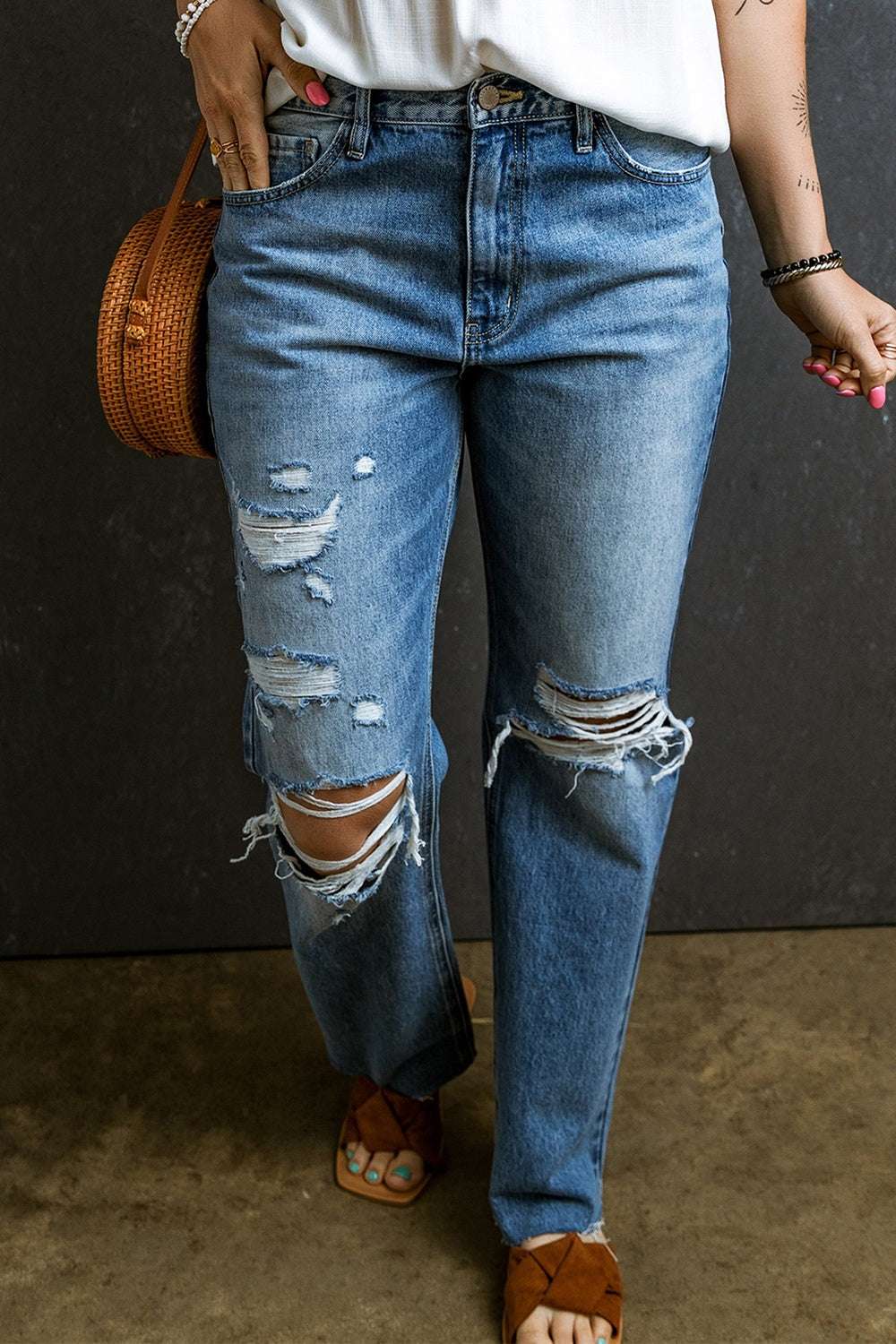 Distressed raw hem jeans with pockets, featuring ripped details and a classic blue wash.
