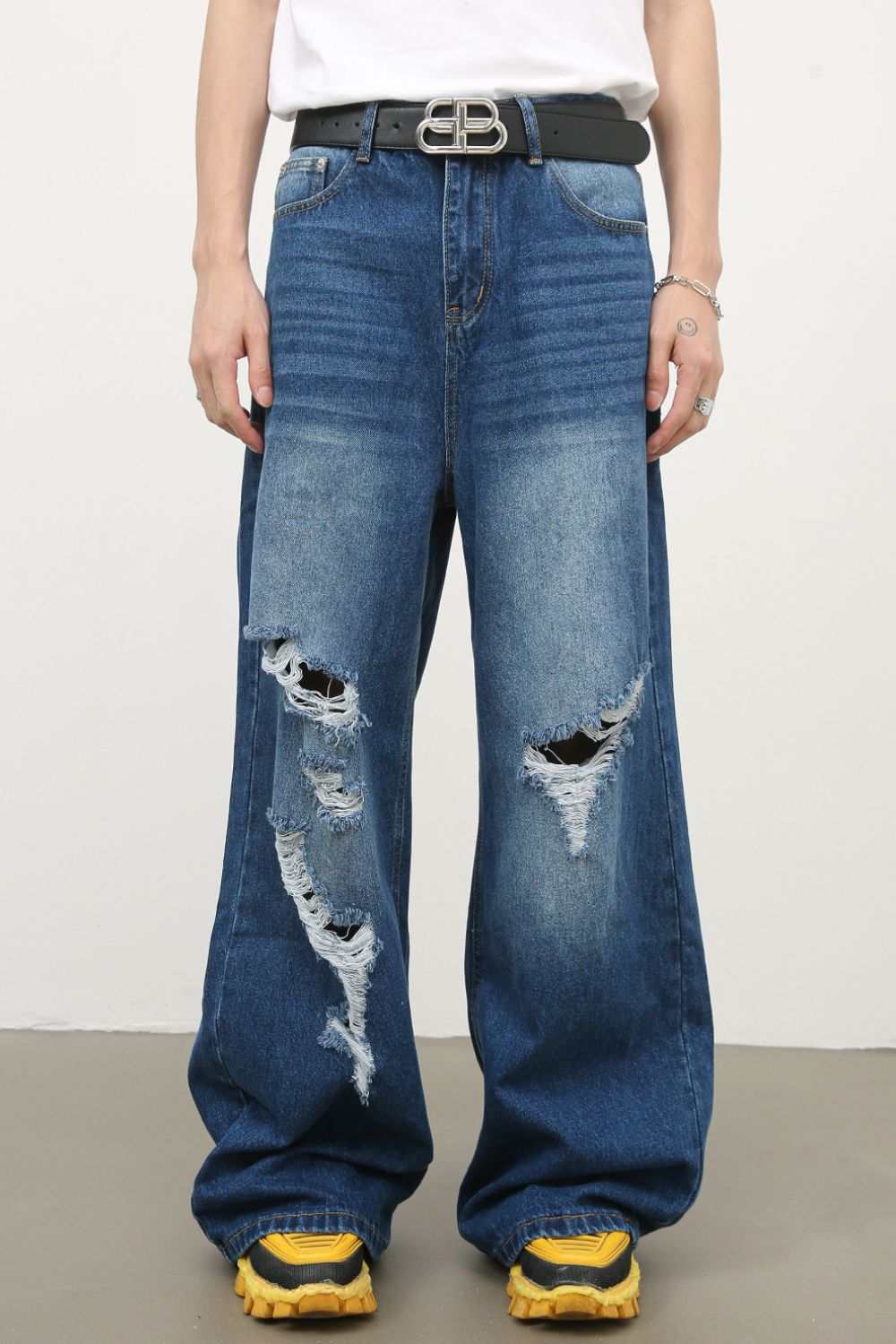 Men's distressed wide leg jeans with raw hem and pockets.