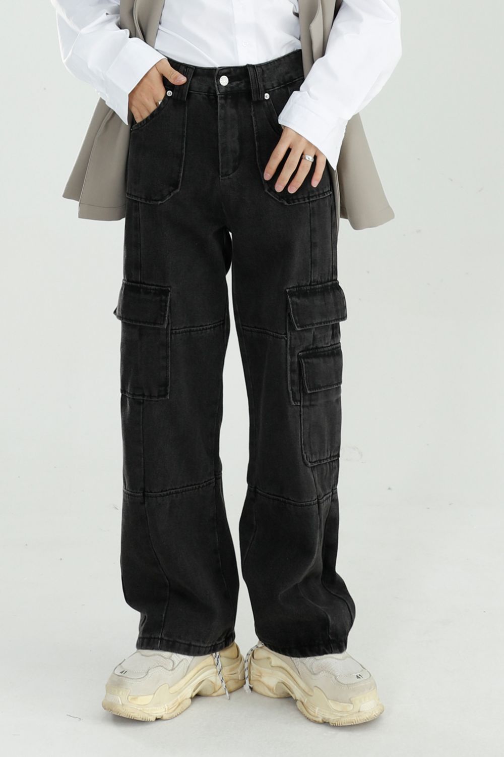 Baggy jeans with cargo pockets in black, no stretch, cotton blend, worn with beige and white top.