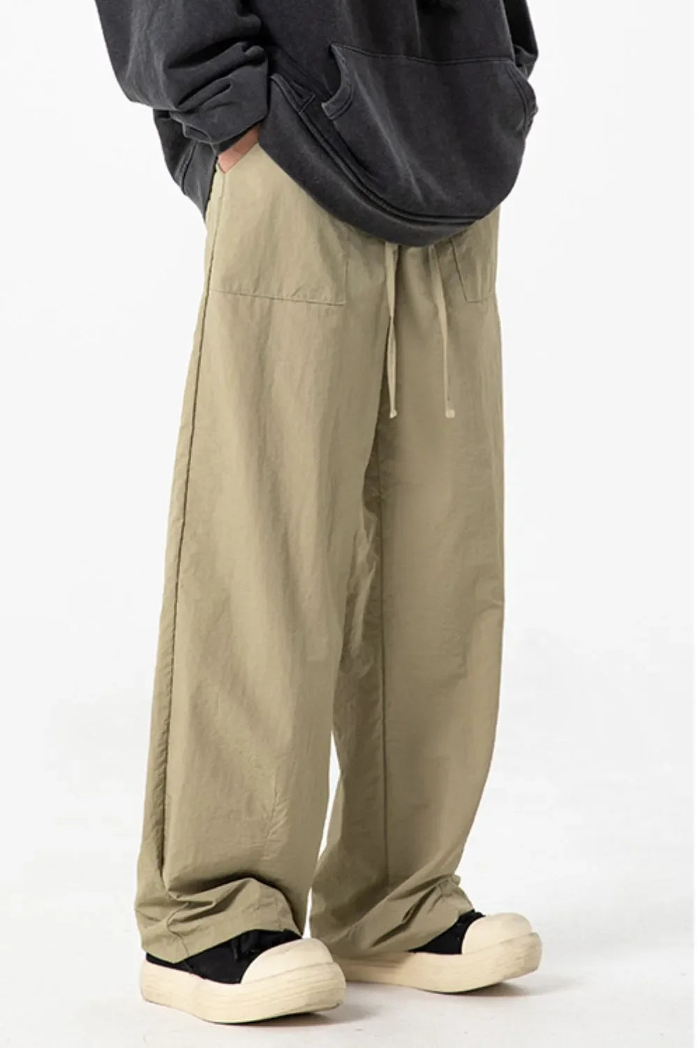 Men's full-size drawstring pants with pockets in beige, worn by a standing person.