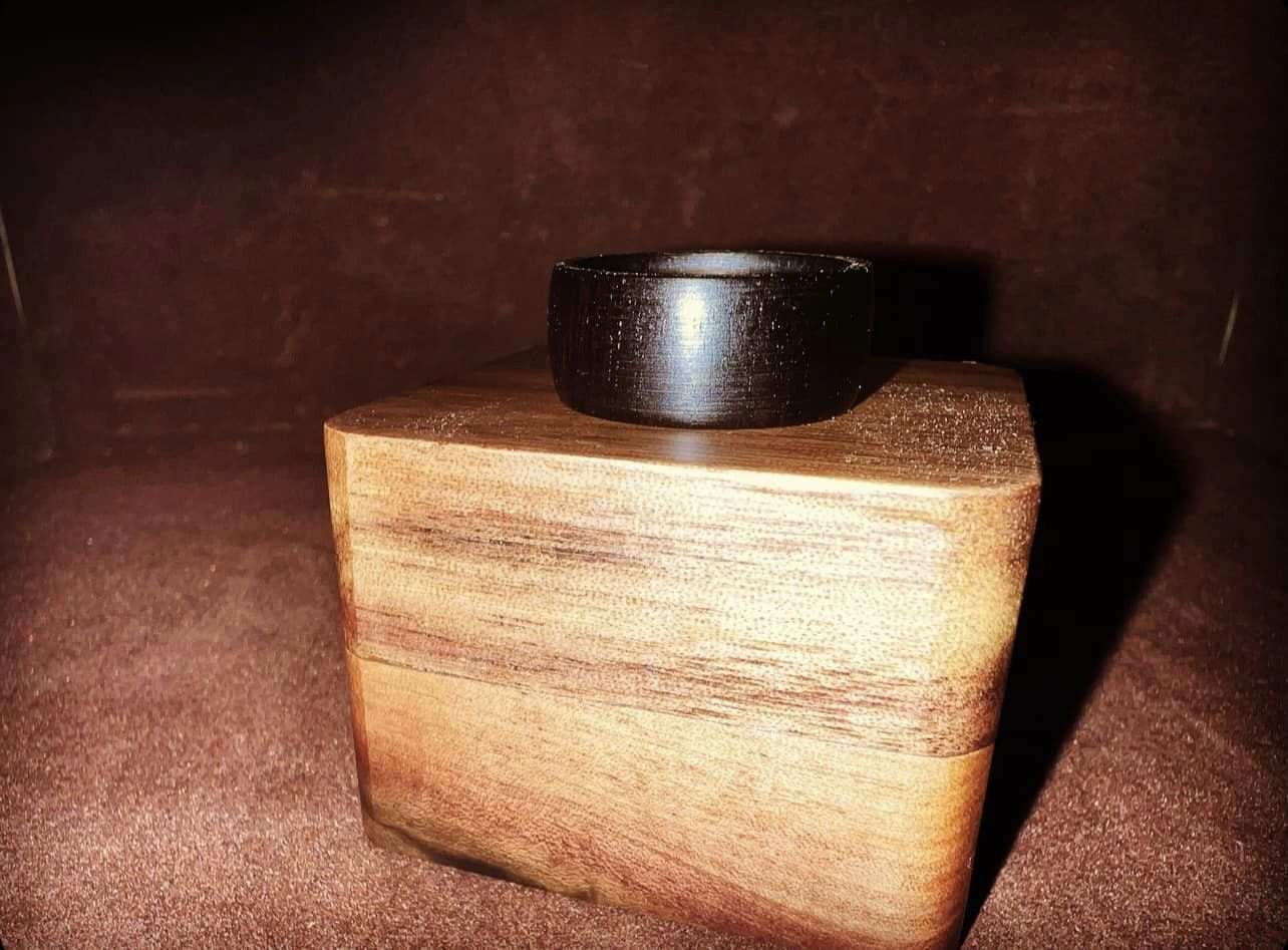 African Blackwood ring displayed on a wooden block, highlighting its rich, dark grain and elegant design.