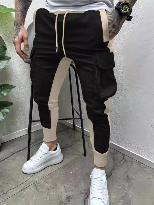 Men's full size contrast drawstring pants in black and beige with pockets, worn with white sneakers.