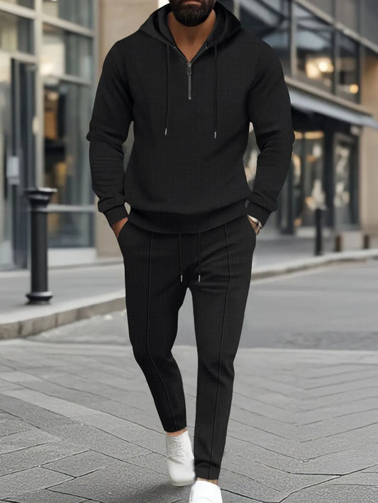 Men's full size waffle-knit half zipper hoodie and pants set in black, featuring drawstring and pockets.