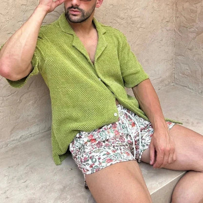 Luxury men's beach wear set with green short-sleeved shirt and floral drawstring shorts.