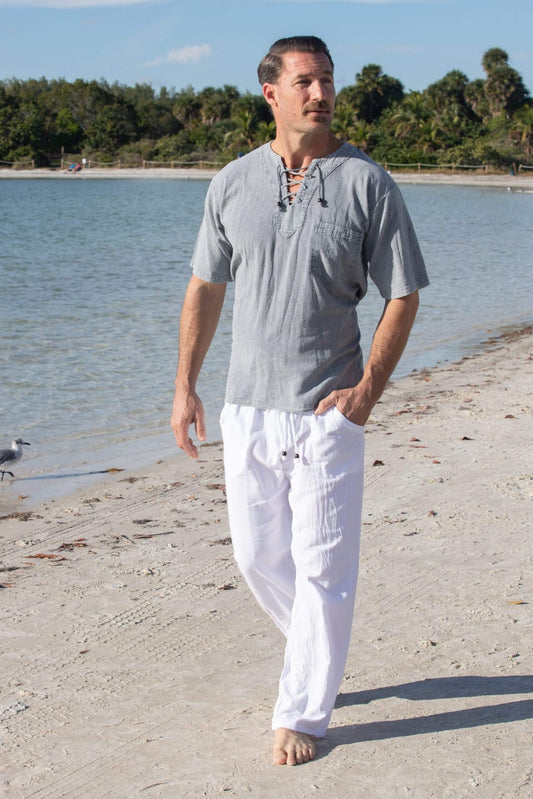 Man wearing Santorini pants on a beach, showcasing long gauze pants made from Peruvian Pima cotton with an elastic waistband and drawstrings.