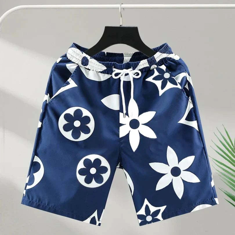 Luxury brand men's beach shorts with bold floral print and drawstring closure hanging on a rack.