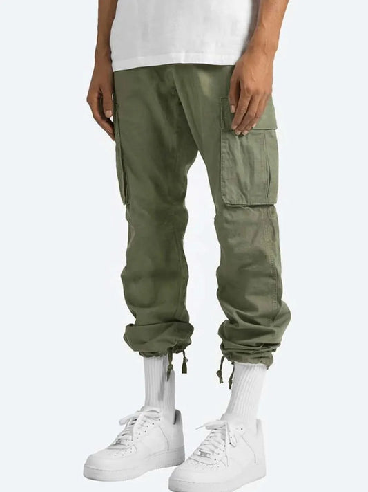 Men's full-size drawstring cargo pants with pockets in olive green paired with white sneakers.