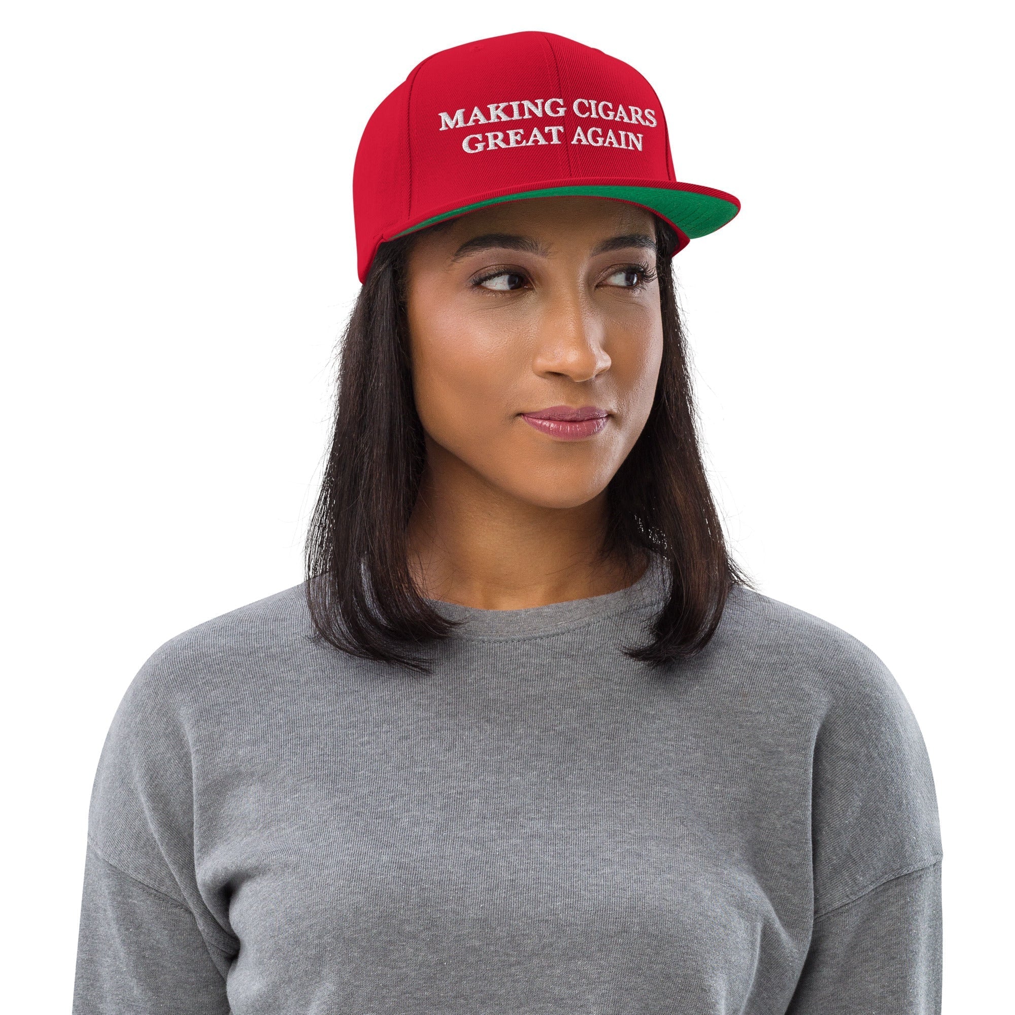 Red snapback hat with "Making Cigars Great Again" text, worn by a person.