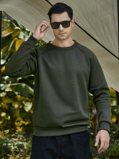 casual raglan sleeve crew neck sweatshirt in olive green on male model outdoors