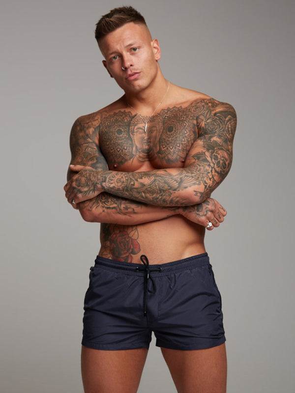 Men's performance leisure shorts for fitness and running, black, modeled by tattooed man, showcasing style and comfort.