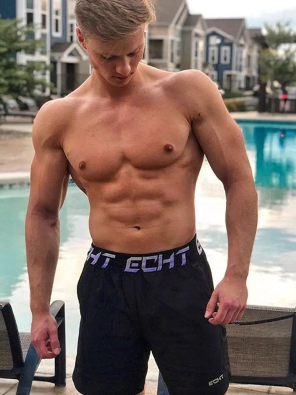 Men's Letter Elastic Waist Active Shorts, stretchy polyester blend, worn by poolside.