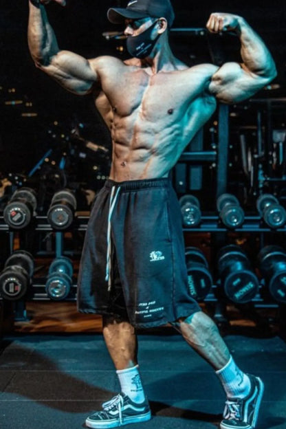 Men's plus size graphic drawstring active shorts in gym setting.
