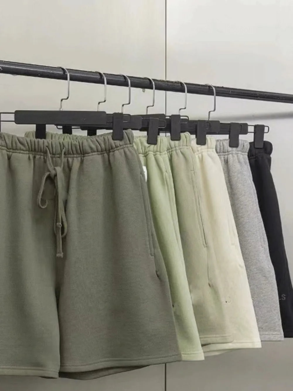 Men's full size drawstring shorts in various colors on hangers.