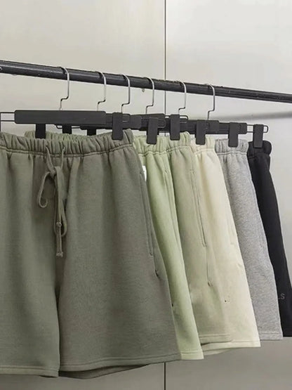 Men's full size drawstring shorts in various colors on hangers.