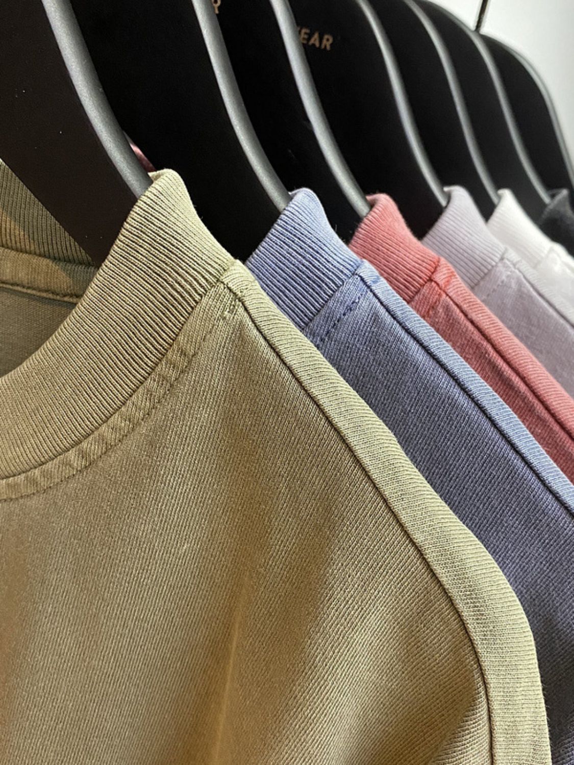 Men's round neck short sleeve t-shirts on hangers in various colors.