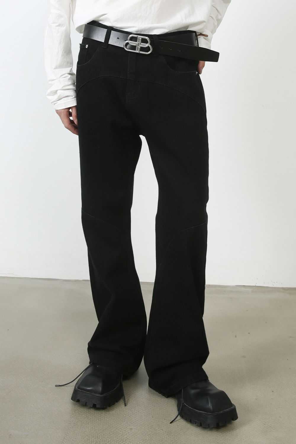 Men's mid rise jeans with pockets, black color, styled with a belt.