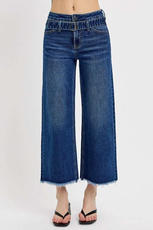 Wide-leg jeans with raw hem and attached buckle detail.