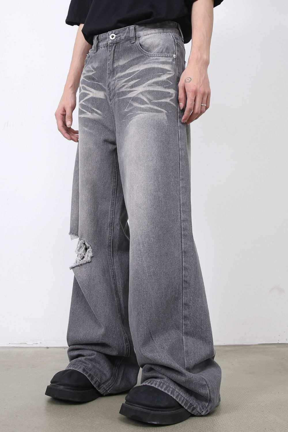 Men's distressed wide leg jeans with raw hem and pockets.