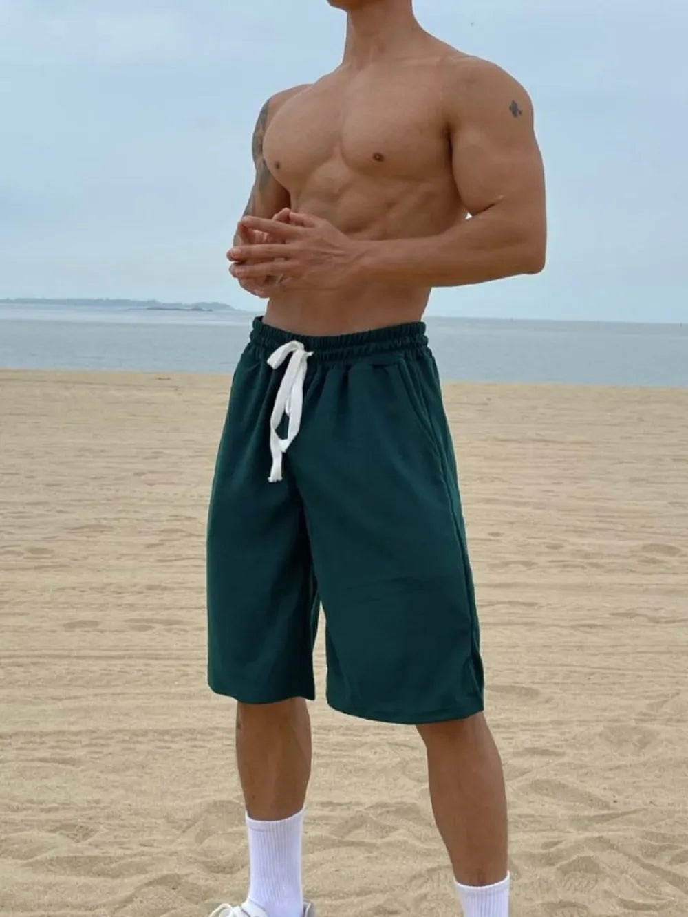 Men's plus size drawstring shorts with pockets on beach.