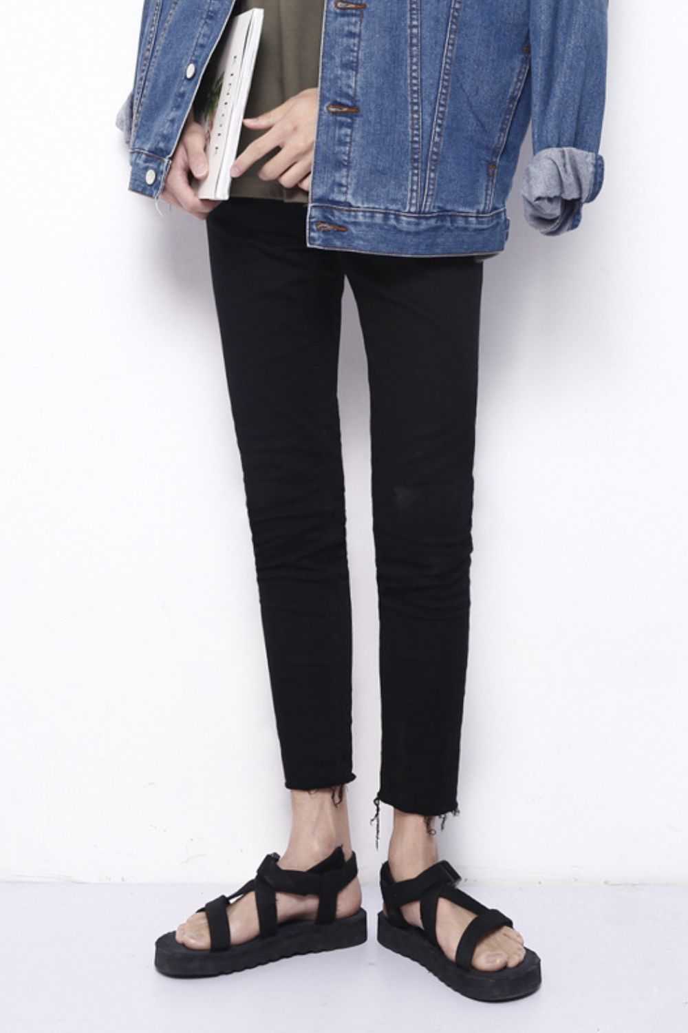 Men's frayed hem skinny jeans with no stretch, paired with a denim jacket and sandals.