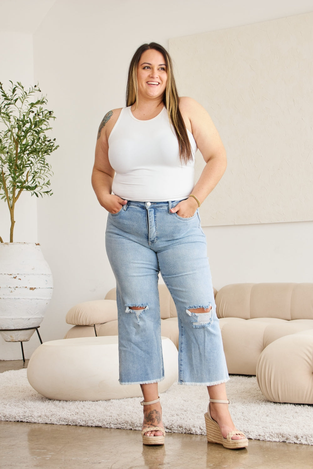 RFM Full Size Tummy Control High Waist Raw Hem Distressed Jeans on a smiling woman in a white tank top and heels.