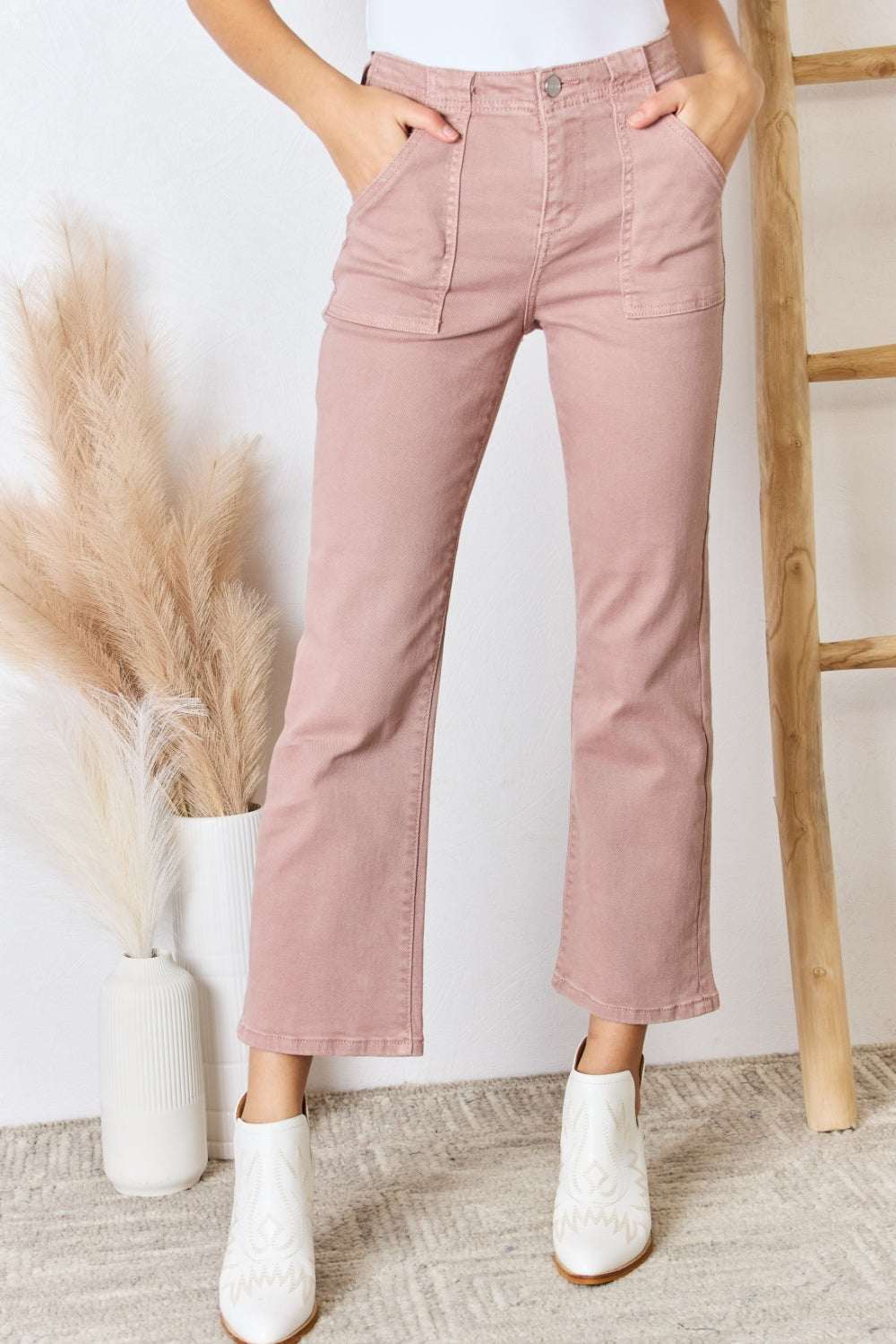 Full size high rise ankle flare jeans in pink fabric displayed with white boots.