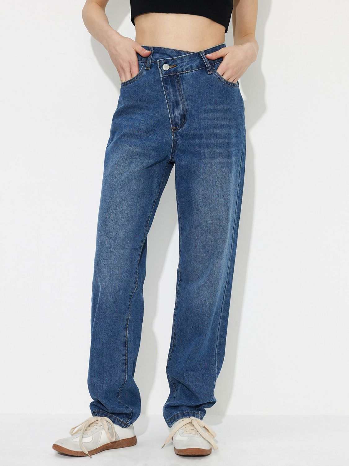 Asymmetric waist jeans with pockets in blue denim, front view.