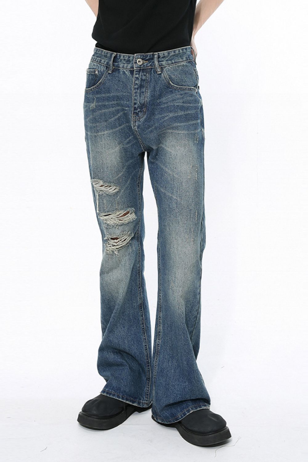Men's distressed bootcut jeans in blue denim with ripped details.
