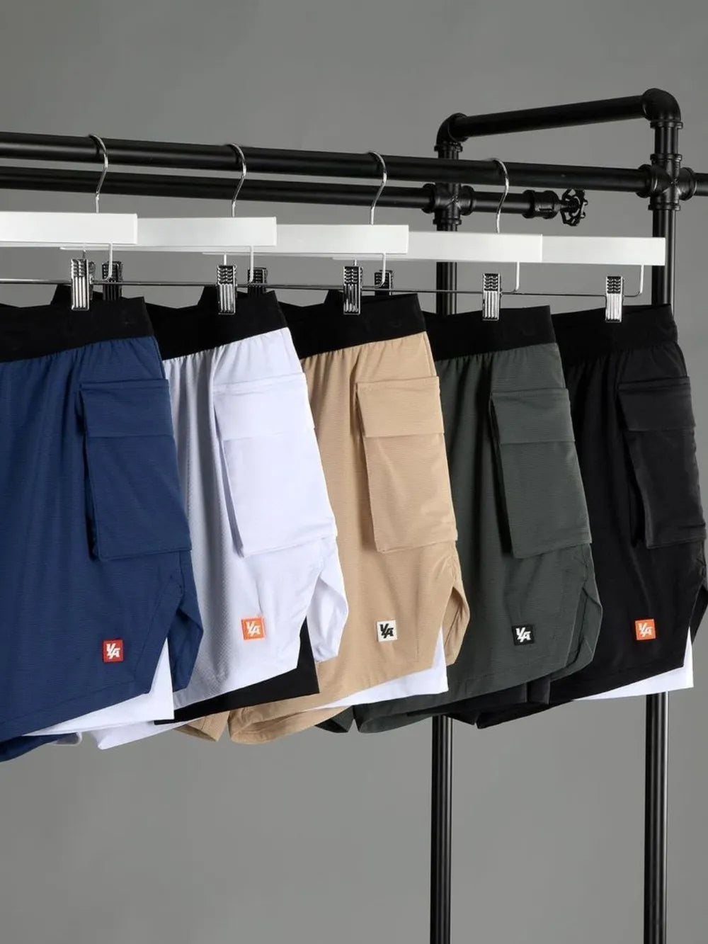 Men's plus size drawstring shorts in blue, white, beige, green, and black hanging on a rack.